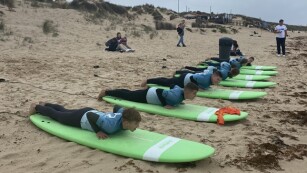 uczniowie leżą na deskach surfingowych