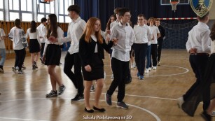 uczniowie tańczą poloneza na sali gimnastycznej