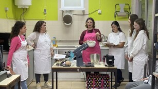 uczniowie słuchają nauczyciela w pracowni kulinarnej