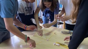 uczniowie układają trójkąt lub piramidę z makaronu spagetti i pianek