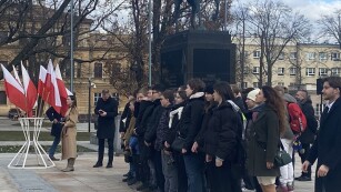 Osoby stoją na placu litewskim, obok stoją flagi Polski