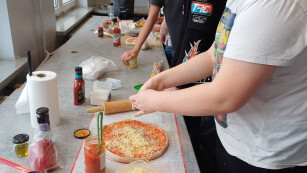 uczniowie układają składniki na pizzy