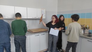 Nauczycielka pokazuje uczniom wałek do ciasta i inne przedmioty w kuchni