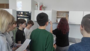 Uczniowie wraz z nauczycielem sprawdzają zawartość górnych szafek kuchennych